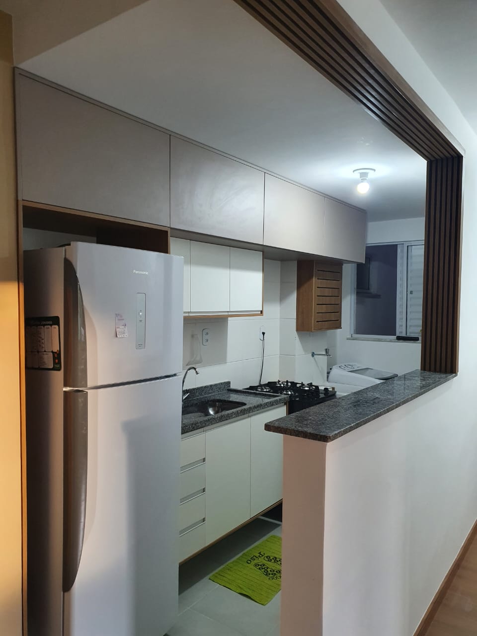 Cozinha planejada americana com passa-prato e painel ripado em madeira em Resende